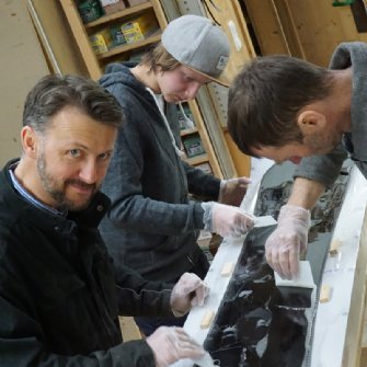Fleißige Hände beim Laminieren eines Snowboards.